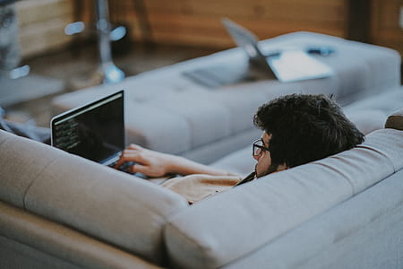 man lying on sofa holding laptop computer thumbnail