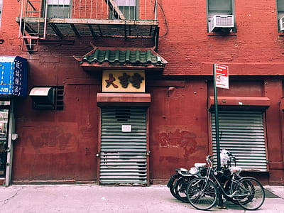 black bicycle and motorcycle parked on post near closed store thumbnail