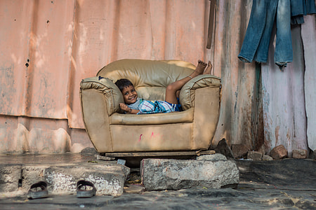 boy laying on brown leather armchair thumbnail