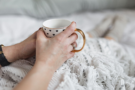 Soft photo of woman on the bed with the book and cup of coffee in hands thumbnail