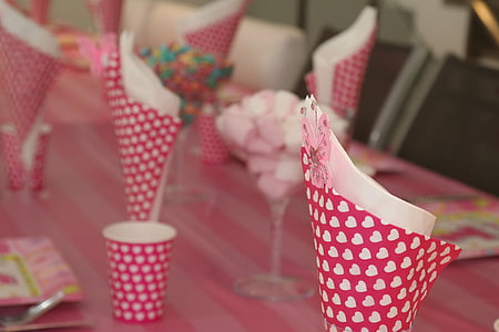 several napkin placed inside of pink heart print cone papers on top of table thumbnail