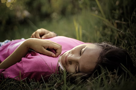 girl wearing pink top lying on grass thumbnail