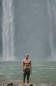 man standing near waterfall during daytime thumbnail