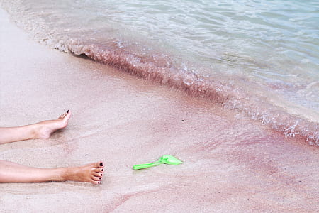 person on beach near at body of water with green plastic shovel thumbnail