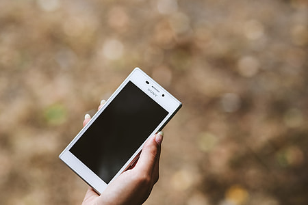 Young woman holding the white mobile phone thumbnail
