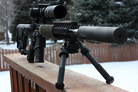 photo of black and brown sniper rifle with scope on wooden baluster during daytime thumbnail