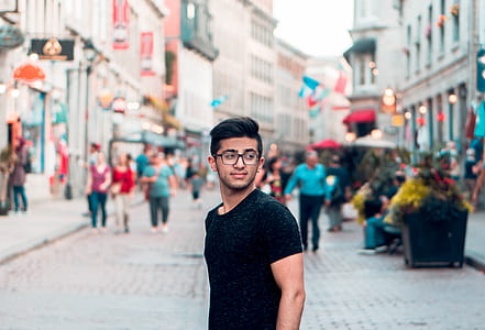 man wearing black crew-neck shirt standing near building thumbnail