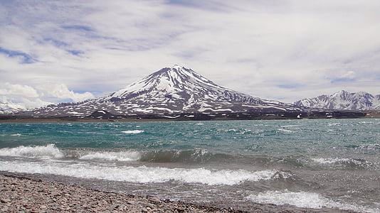 body of water near mountain under gray sky thumbnail