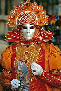 person in brown and orange traditional outfit holding fan thumbnail