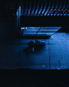 person holding black luggage bag walking beside establishment during nighttime thumbnail