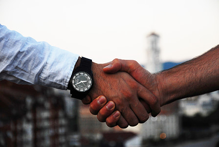 two persons shaking hands during daytime thumbnail