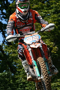 person riding dirt bike beside tree during daytime thumbnail