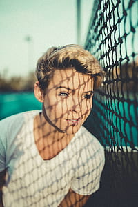 shallow focus photography of girl standing beside net thumbnail