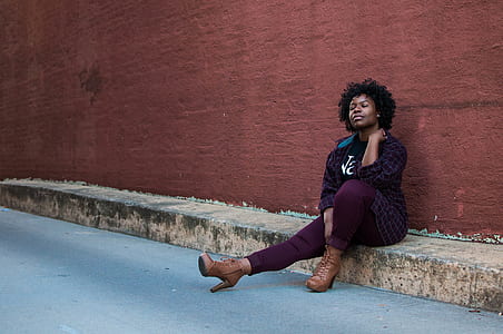 woman sitting on street while left hand on her neck thumbnail