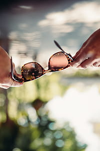 Sunglasses held by female hands with bokeh background thumbnail
