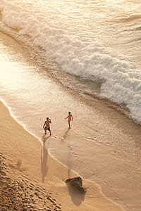couple walking on seashore aerial photography thumbnail