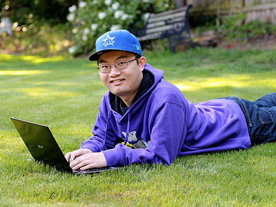 man using laptop computer on grass field thumbnail