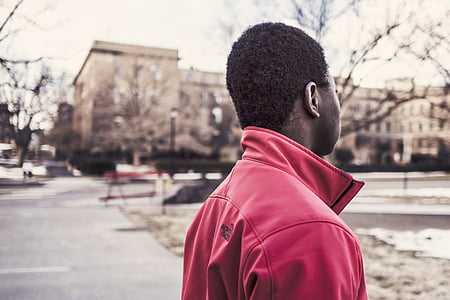 man wearing red jacket while standing on road thumbnail