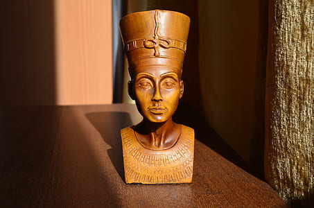 brown wooden Egyptian headbust on brown wooden table closeup photo thumbnail