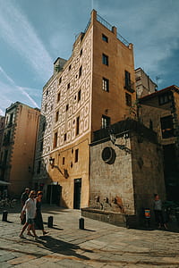 Man and Woman Walking Near Brown Concrete Building thumbnail