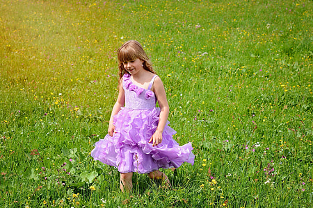 girl wearing purple dress standing on green grass field during daytime thumbnail