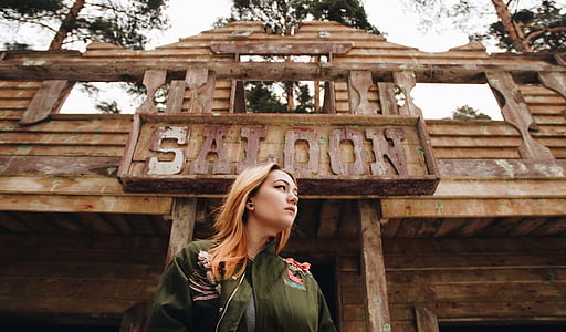 woman wearing green jacket standing outside saloon bar at daytime thumbnail