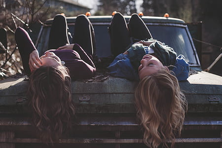 two woman lying on vehicle at daytime thumbnail