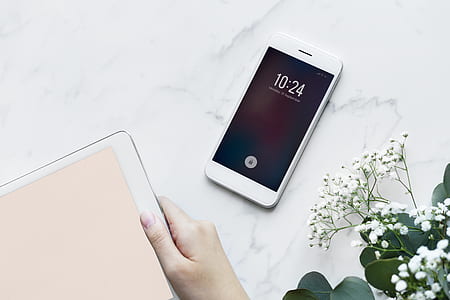 turned on white Android smartphone on white surface beside white petaled flowers thumbnail
