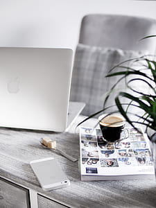 Silver Iphone Beside Book Under Cup Beside Silver Macbook thumbnail