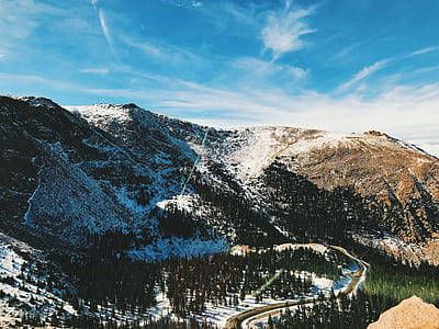 mountain range with railroad surrounded by pine trees under blue sky at daytime thumbnail