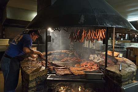 man grilling food on charcoal grill in building thumbnail