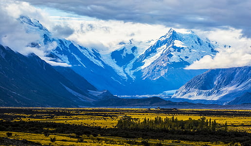 snow covered mountain near grass field terrain thumbnail