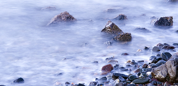 time lapse photography of body of water surrounded with rocks thumbnail