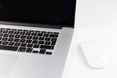 Apple Macbook Pro laptop computer and Magic Mouse situated on a minimalist pure white wood desk thumbnail
