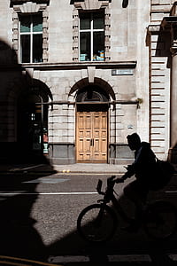 man riding bicycle near concrete building thumbnail