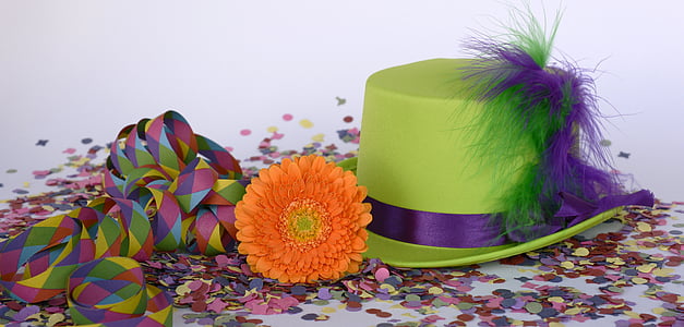 green and purple hat beside orange flower on top of confetti thumbnail