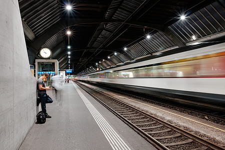 man leaning on wall beside train rail on train station thumbnail