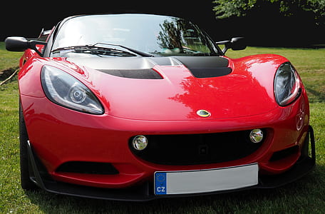 red Lotus convertible coupe on green grass field at daytime thumbnail