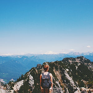 person wearing black backpack standing on mountain thumbnail