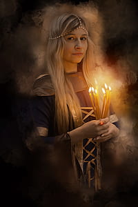 woman wearing black and beige long-sleeved dress holding lighted candles thumbnail