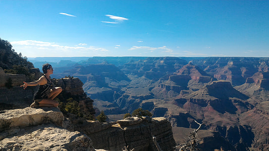 photography of woman on rock formation under blue sky thumbnail