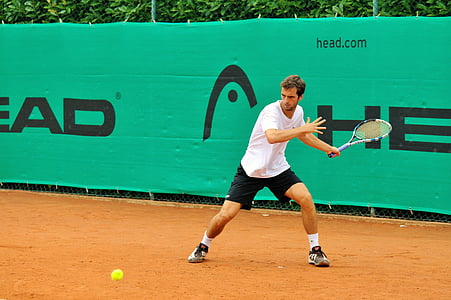 tennis player wearing white shirt looking at the ball bouncing thumbnail