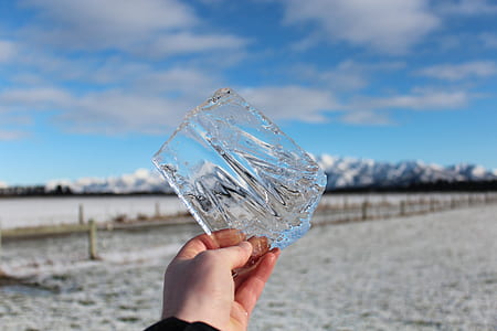 person holding clear cut glass fragment during daytime thumbnail