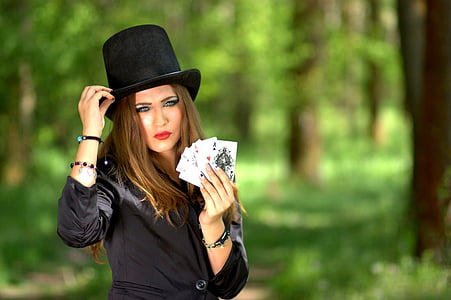 woman holding playing card standing near trees during daytime thumbnail