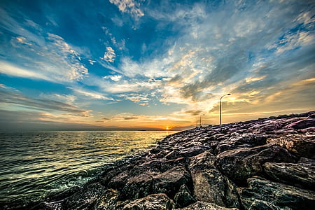 body of water beside boulders thumbnail