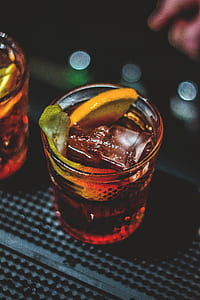 brown liquid in clear drinking glass with sliced lime on top thumbnail