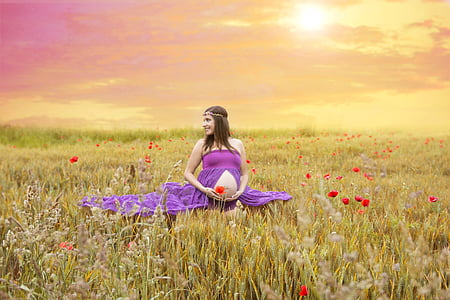 pregnant woman in purple dress sitting on green grass field during daytime thumbnail