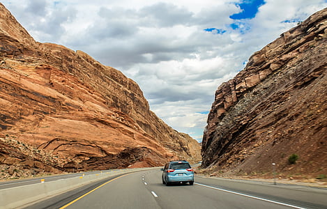 blue SUV passing near brown rock formation during daytime thumbnail