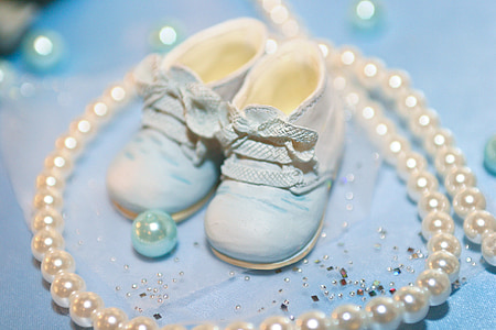 baby's white shoes surrounded by white pearls thumbnail
