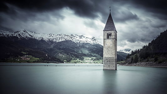 white concrete tower in body of water under gray clouds thumbnail